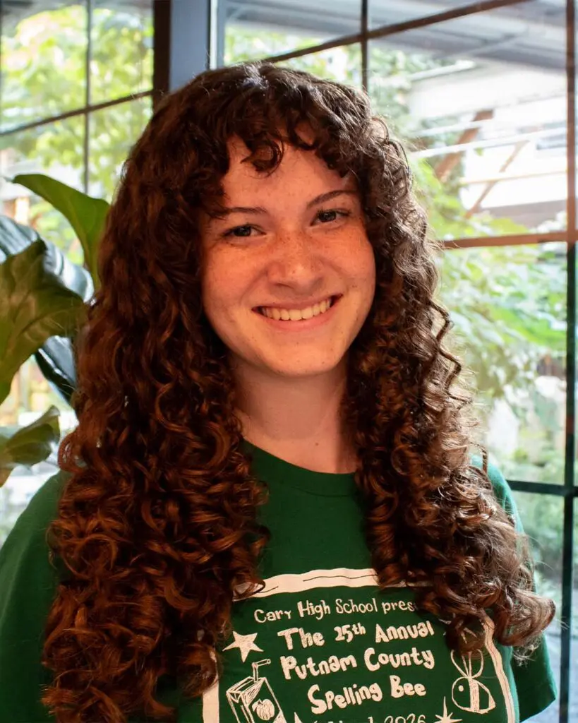 Voluminous rich chestnut curly shag with defined ringlets and full curtain fringe crafted at Sunday Salon located in Raleigh.