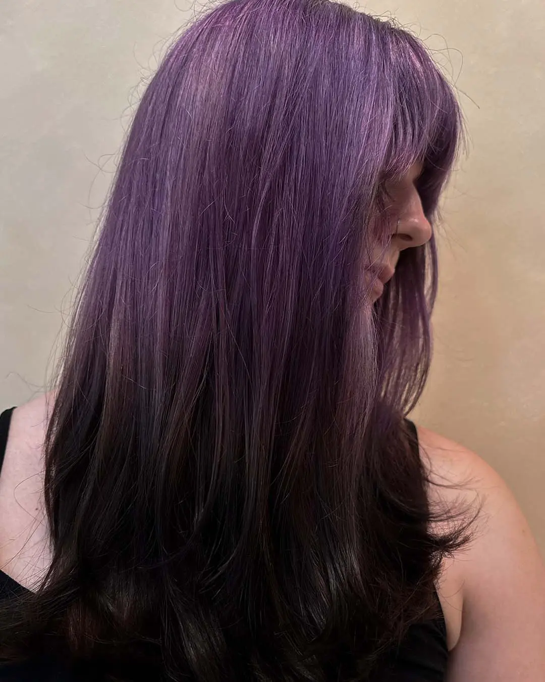 Soft Lavender to Dark Espresso Ombre with Full Fringe A profile view of long straight hair featuring a muted lavender crown melting into dark espresso ends with a full fringe, styled at Sunday Salon in Raleigh.