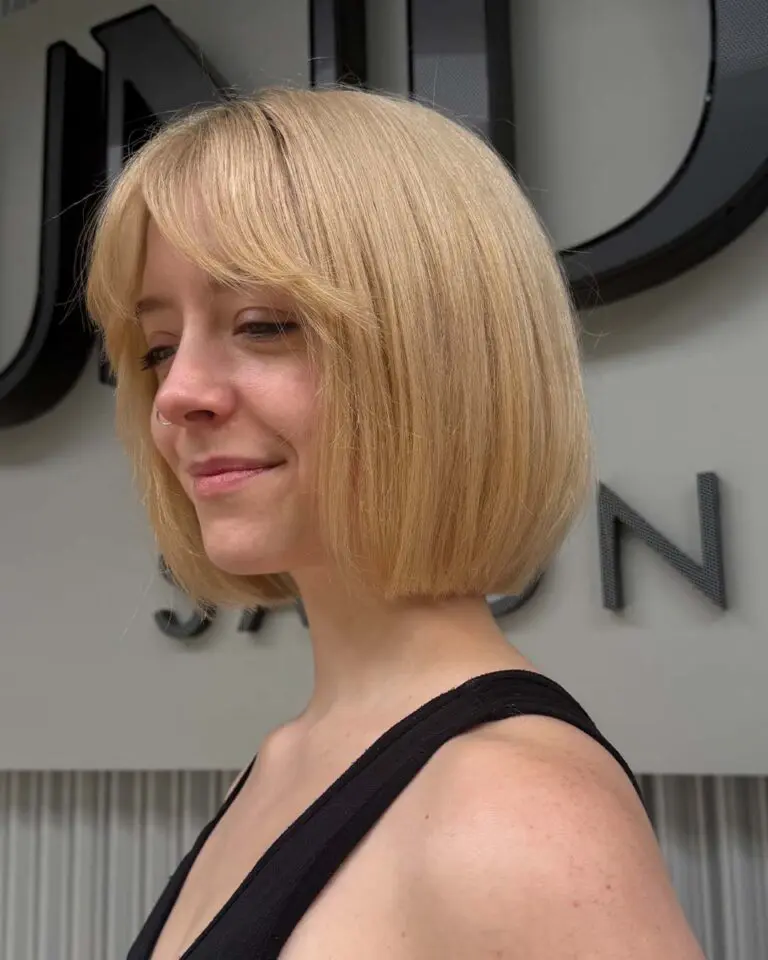Client featuring a bright butter blonde chin-length French bob with curtain bangs created at Sunday Salon in Raleigh.