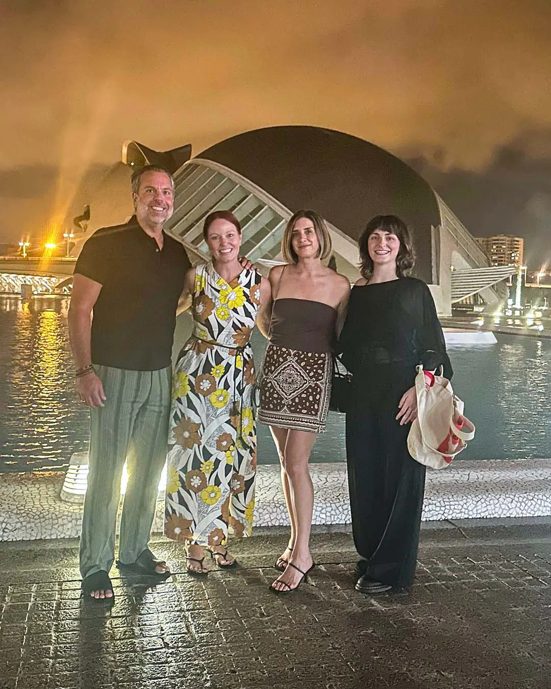 davines-europe-1 Four adults stand side-by-side on a paved walkway at night in front of the City of Arts and Sciences in Valencia, Spain.