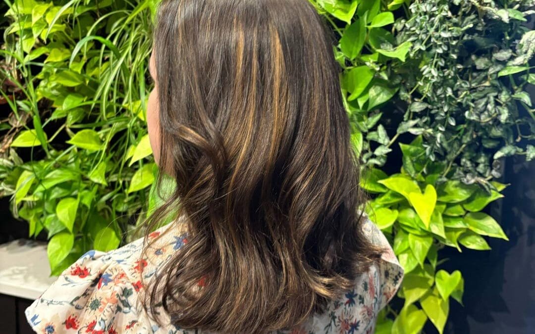 A client at Sunday Salon in Raleigh showcasing a bouncy shoulder-length style with a deep chocolate brown base and warm caramel ribbon highlights.