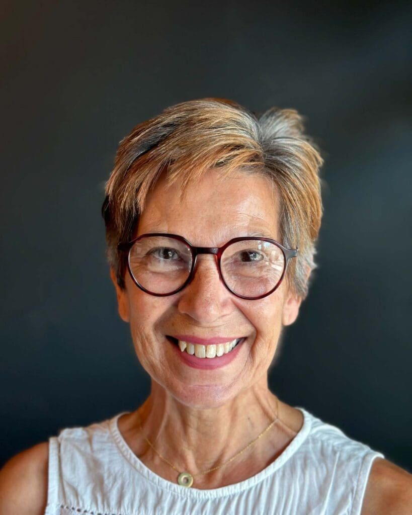 A smiling client showcasing a chic, short textured pixie haircut with beautifully blended natural silver and warm copper tones, crafted at Sunday Salon in Raleigh.